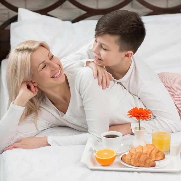 Alto ángulo madre sorprendida en la cama con desayuno