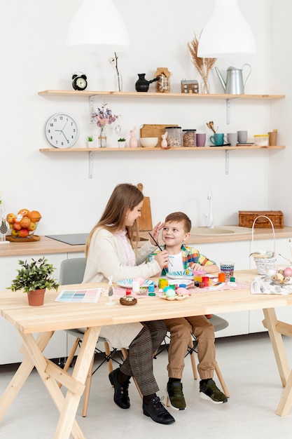 Alto ángulo mamá e hijo pintando huevos para pascua