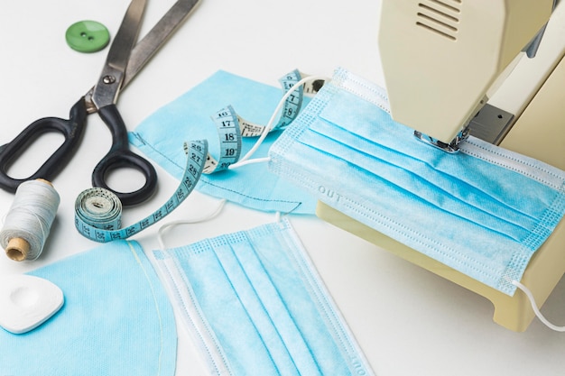 Foto gratuita alto ángulo de máquina de coser con máscara médica y tijeras