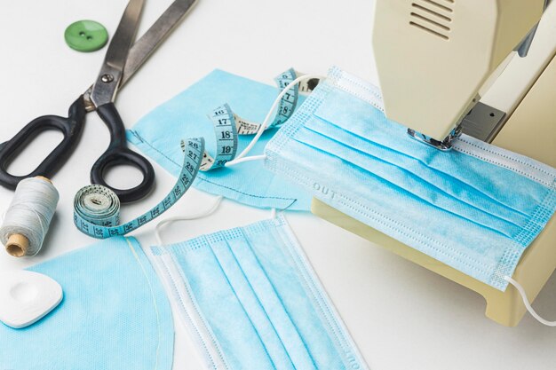Alto ángulo de máquina de coser con máscara médica y tijeras