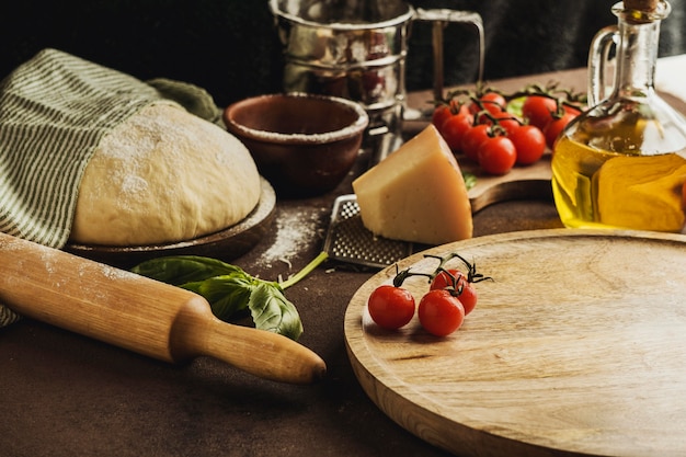 Alto ángulo de masa de pizza con tabla de madera y queso parmesano