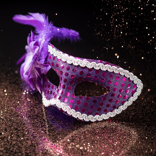 Alto ángulo de máscara de carnaval con purpurina y plumas.