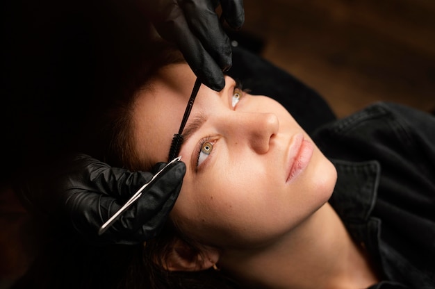 Alto ángulo de médico femenino haciendo un tratamiento de cejas para clienta