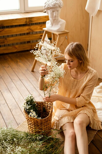 Alto ángulo de mujer con canasta y flores de primavera