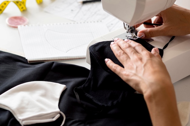 Alto ángulo de mujer cosiendo mascarilla de textil