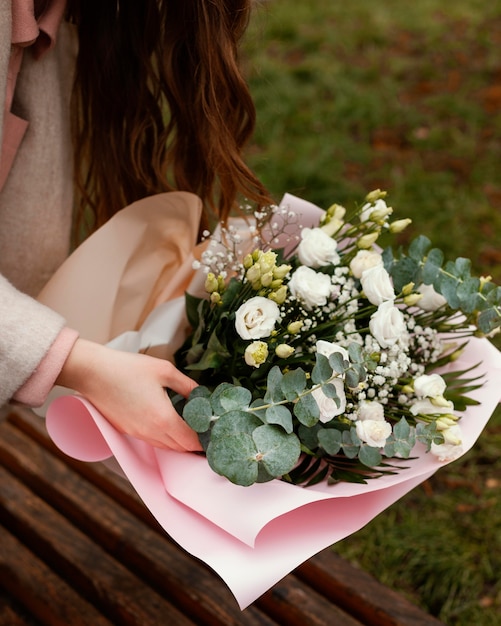 Alto ángulo de mujer elegante con ramo de flores al aire libre