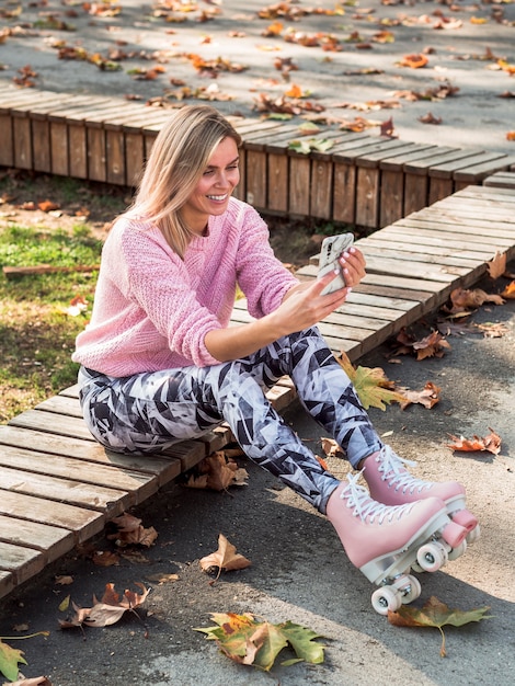 Foto gratuita alto ángulo de mujer en mallas y patines tomando selfie