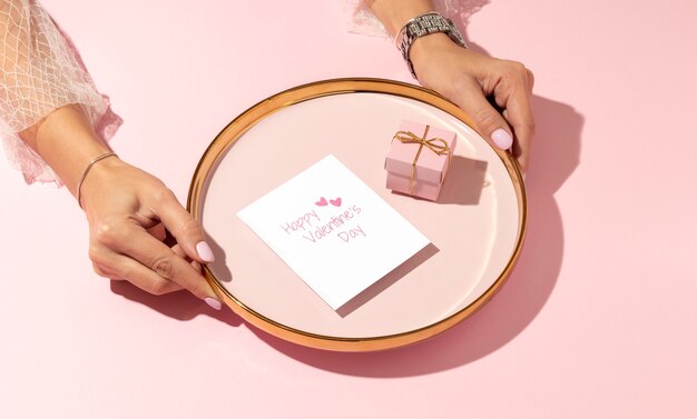 Alto ángulo de mujer ofreciendo caja de regalo en placa para el día de San Valentín