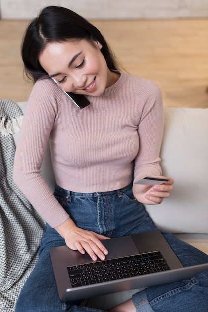 Foto gratuita alto ángulo de mujer ordenando en línea mientras habla por teléfono