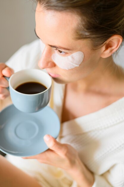 Alto ángulo de mujer con parches en los ojos tomando café