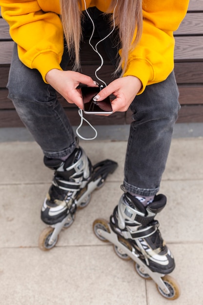 Foto gratuita alto ángulo de mujer en patines mirando smartphone