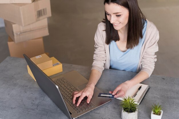 Alto ángulo de mujer trabajando con laptop y cajas