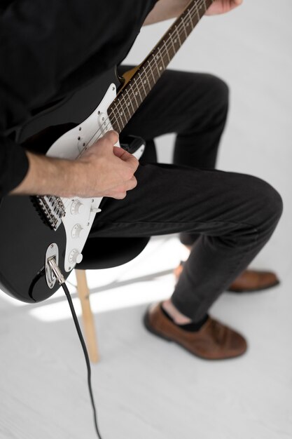 Alto ángulo de músico masculino tocando la guitarra eléctrica