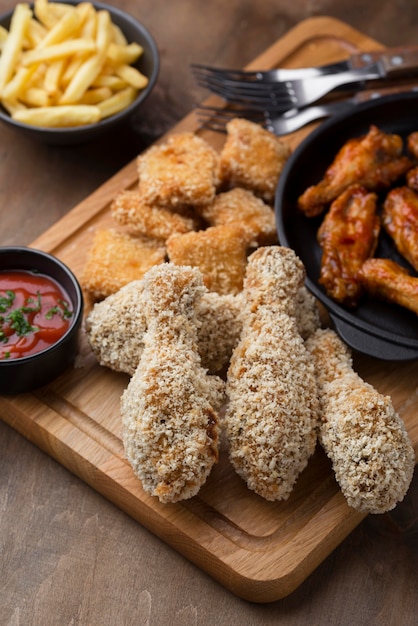 Alto ángulo de muslos de pollo frito con salsa y patatas fritas