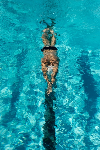 Alto ángulo de nadador masculino nadando en la piscina de agua