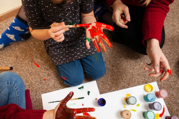 Foto gratuita alto ángulo de niña pintando su palma