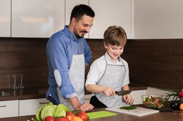 Alto ángulo padre e hijo cortando verduras