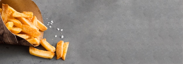 Alto ángulo de papas fritas con sal y espacio de copia