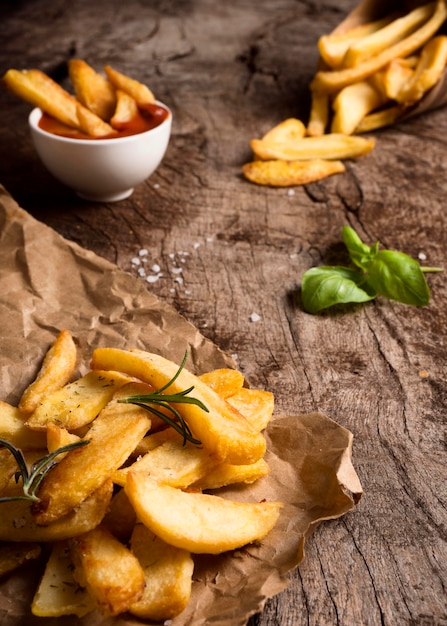 Alto ángulo de papas fritas saladas con salsa de tomate y hierbas