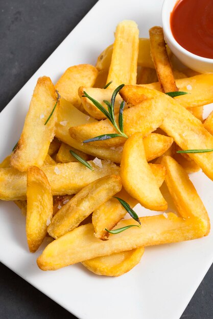 Alto ángulo de papas fritas con salsa de tomate y hierbas