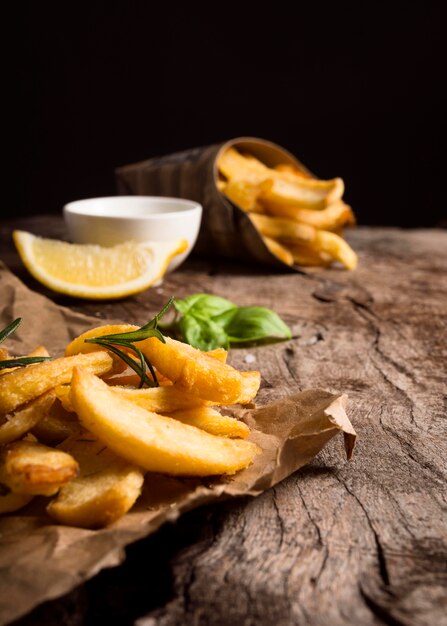 Alto ángulo de papas fritas sobre papel con salsa