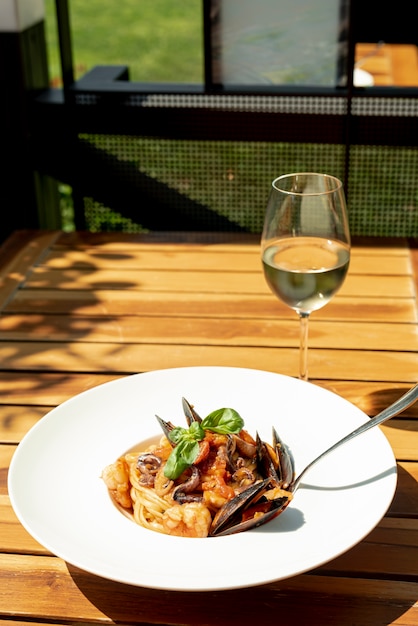 Alto ángulo de pasta y vino en mesa de madera