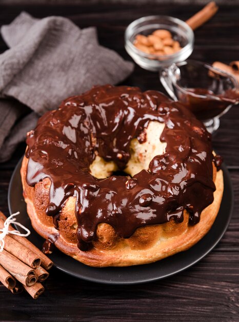 Alto ángulo de pastel con cobertura de chocolate y palitos de canela