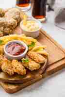 Foto gratuita alto ángulo de patas de pollo frito y nuggets con bebidas gaseosas y papas fritas