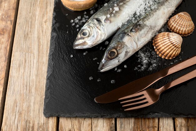 Alto ángulo de pescado en pizarra con cubiertos