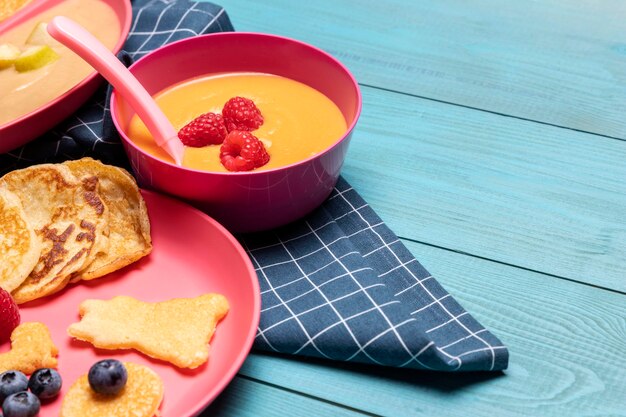 Alto ángulo de plato con comida para bebés y frutas.