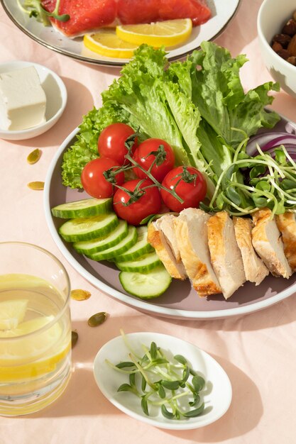 Alto ángulo de plato con comida cetogénica y un vaso de agua con limón