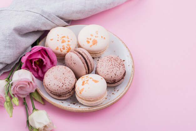 Alto ángulo de plato con macarons y rosas