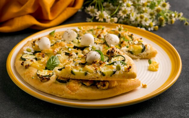 Alto ángulo de plato de pizza con flores de manzanilla