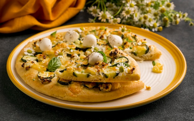 Alto ángulo de plato de pizza con flores de manzanilla