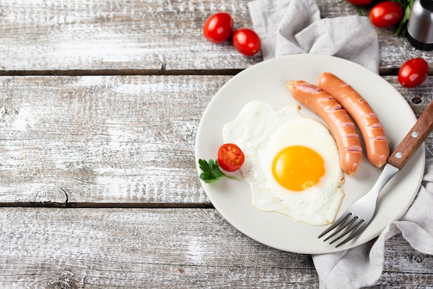 Alto ángulo de plato con salchichas y huevo para el desayuno.