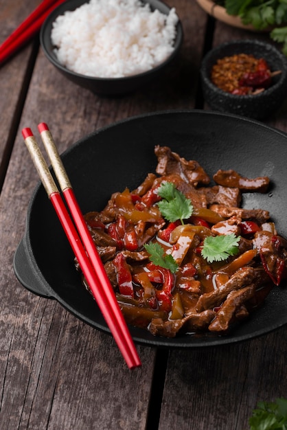 Alto ángulo de plato tradicional asiático con carne y palillos