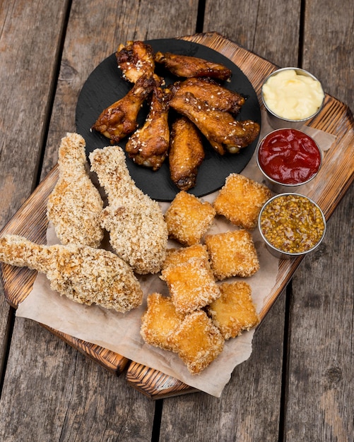 Alto ángulo de pollo frito con nuggets y tres salsas