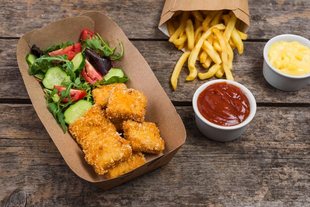 Alto ángulo de pollo frito con papas fritas y ensalada