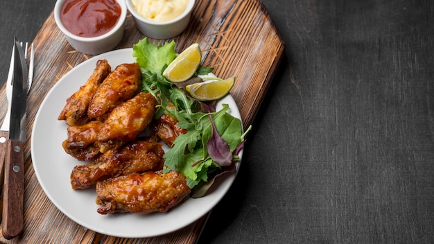 Foto gratuita alto ángulo de pollo frito con salsa y ensalada en la placa