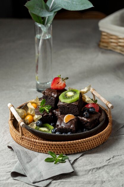 Alto ángulo de postres de frutas en placa con jarrón y planta