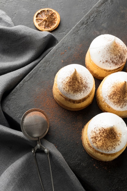 Foto gratuita alto ángulo de postres en pizarra con cacao en polvo y tamiz