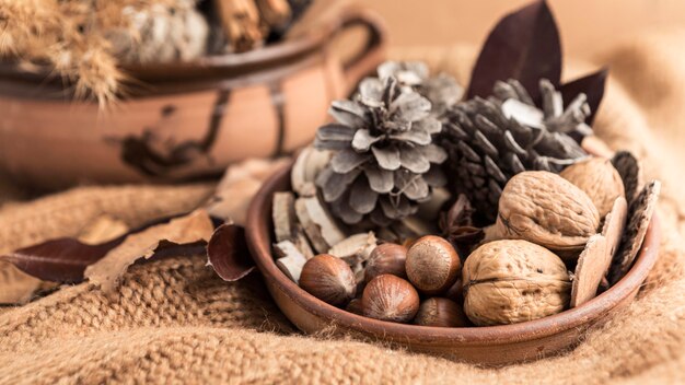 Alto ángulo del recipiente con nueces y piñas sobre arpillera