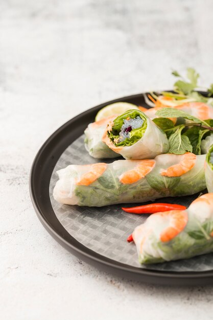 Alto ángulo de rollos de camarones en un plato con salsa