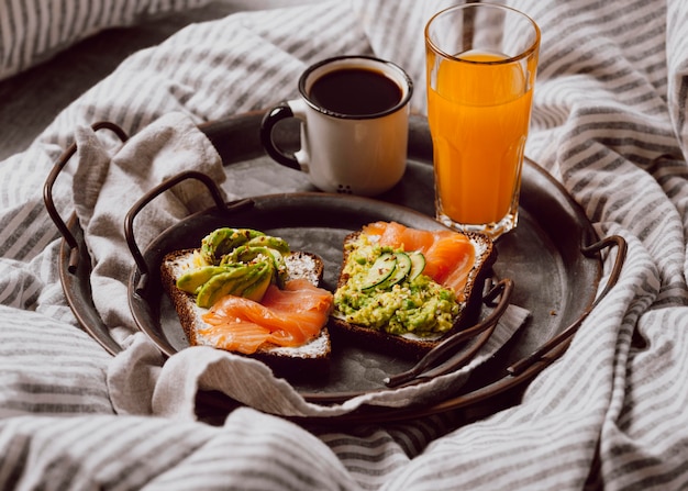 Alto ángulo de sándwiches de desayuno en la cama con aguacate y salmón