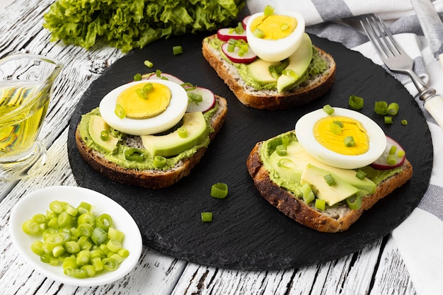 Alto ángulo de sándwiches en pizarra con huevo y aguacate