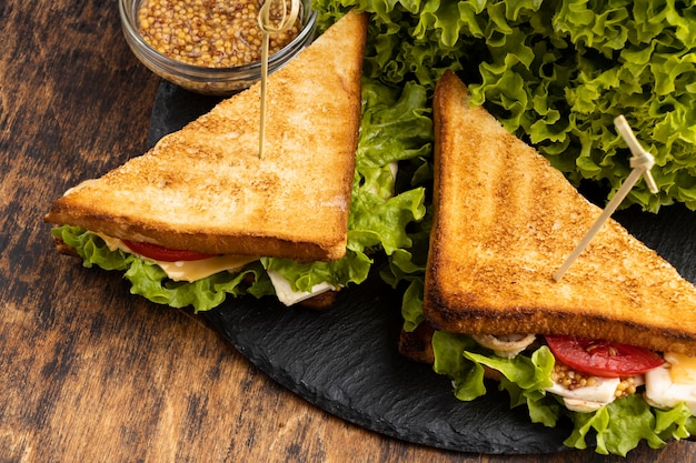 Alto ángulo de sándwiches triangulares en pizarra con ensalada