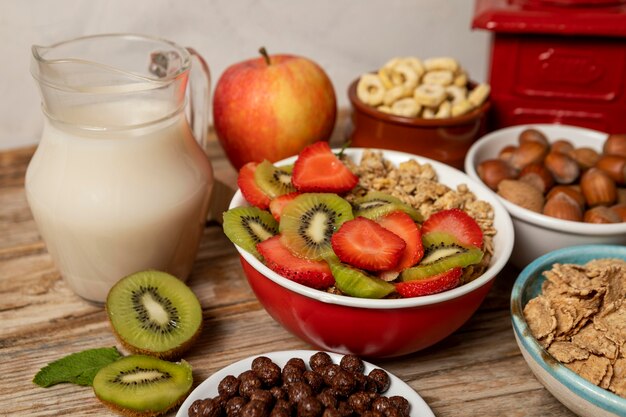 Alto ángulo de selección de cereales para el desayuno en un tazón con frutas y leche