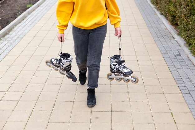 Alto ángulo sobre mujer sosteniendo patines mientras camina