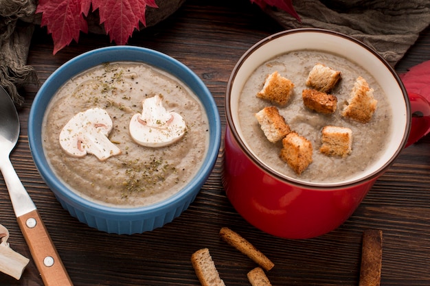 Alto ángulo de sopa de setas de invierno en taza y tazón con crutones