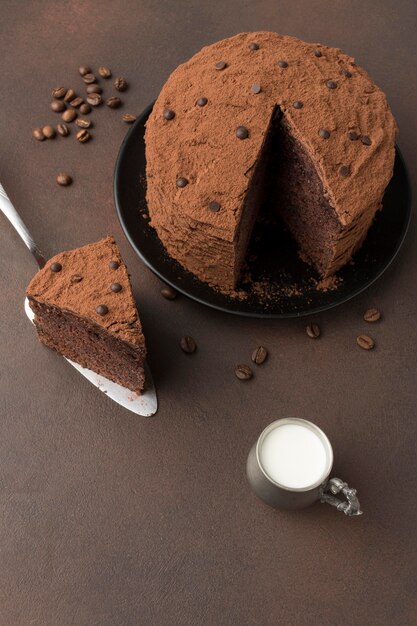 Alto ángulo de tarta de chocolate con cacao en polvo y leche